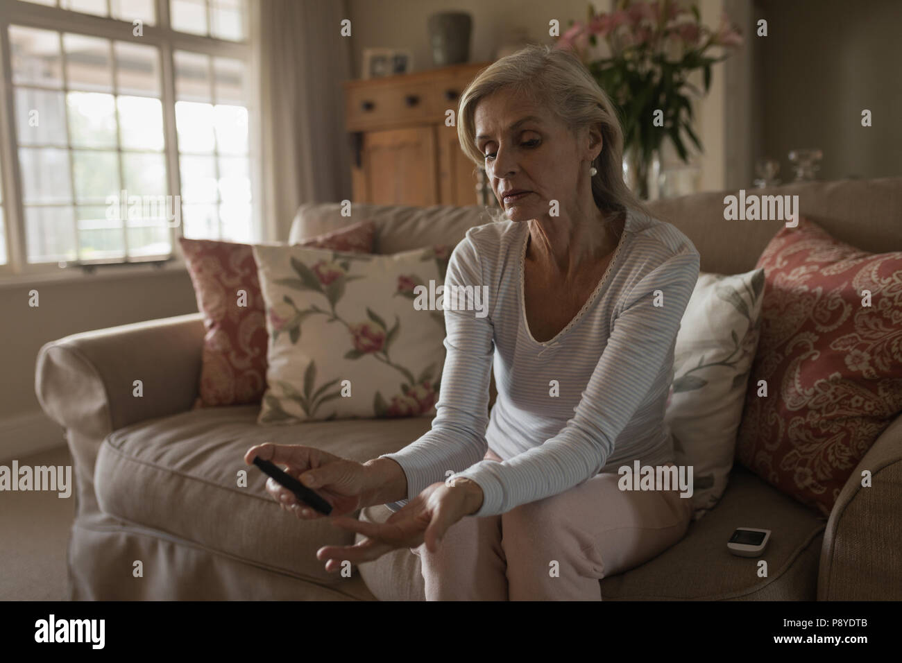 Senior woman with glucomètre contrôler le niveau de sucre dans le sang à la maison Banque D'Images