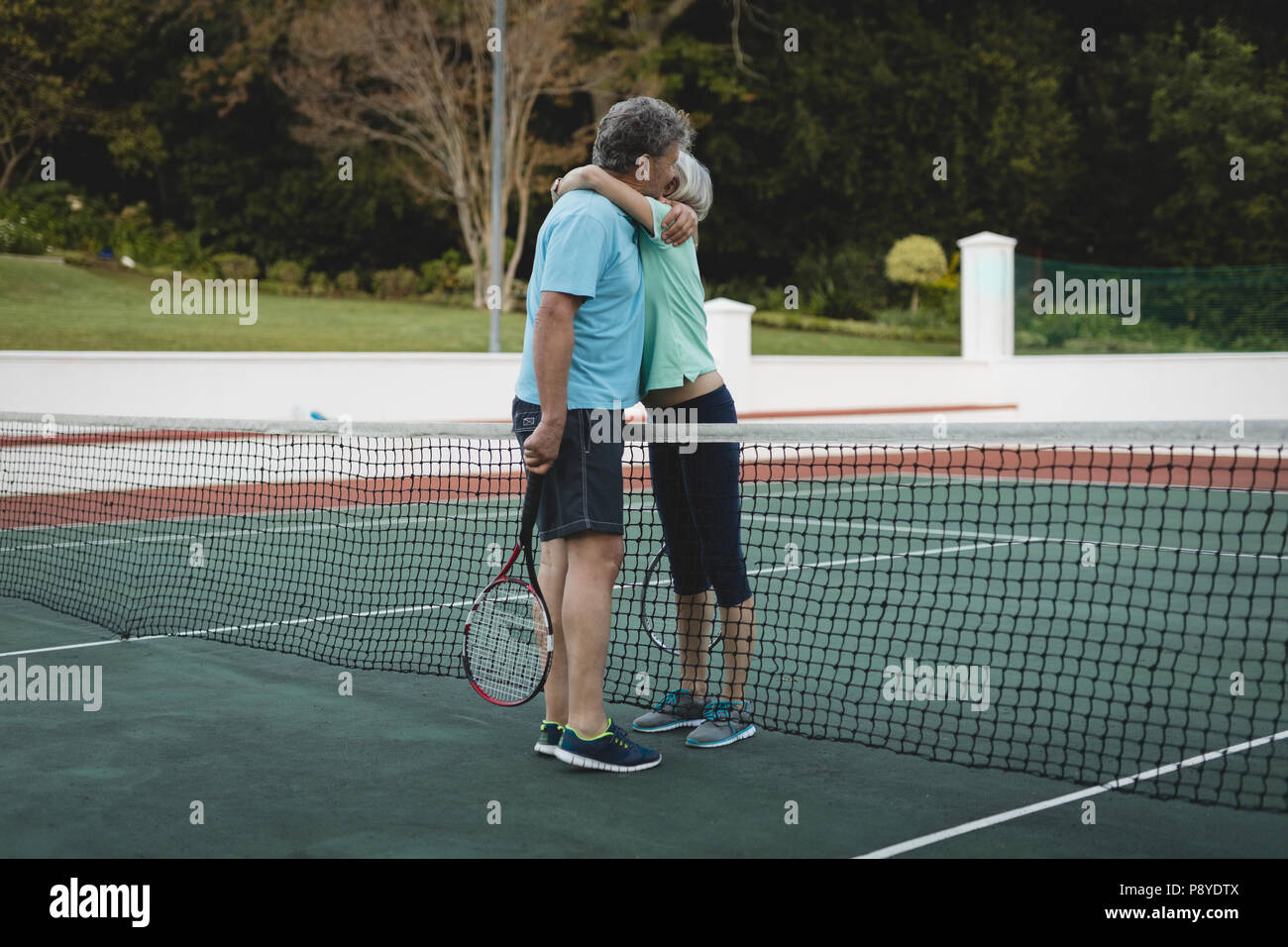 Senior couple hugging in tennis Banque D'Images