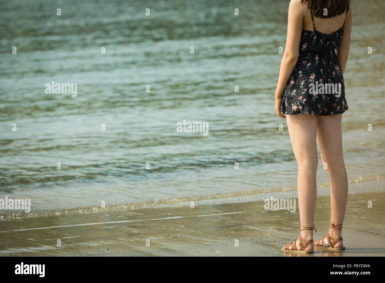 Femme debout sur la plage par une journée ensoleillée Banque D'Images