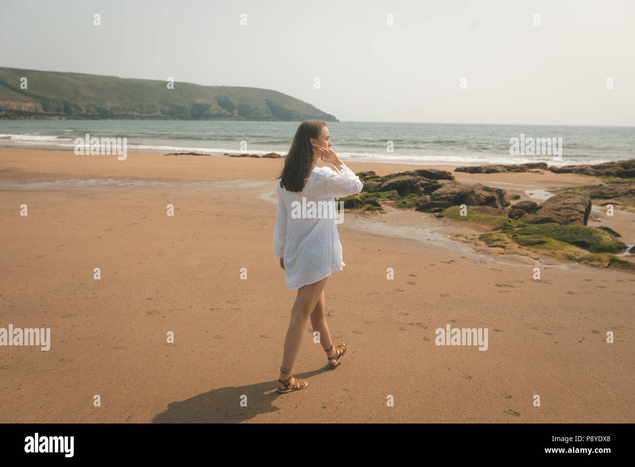 Femme marche sur la plage par une journée ensoleillée Banque D'Images