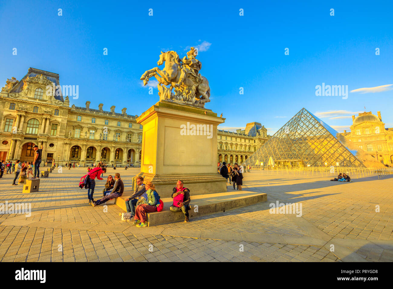 Paris, France - 1 juillet 2017 : Plomb copie de Bernini statue équestre du roi Louis XIV sur la place des Palais du Louvre par l'aile Denon contenant le chef d'oeuvre de Léonard de Vinci Mona Lisa. Banque D'Images