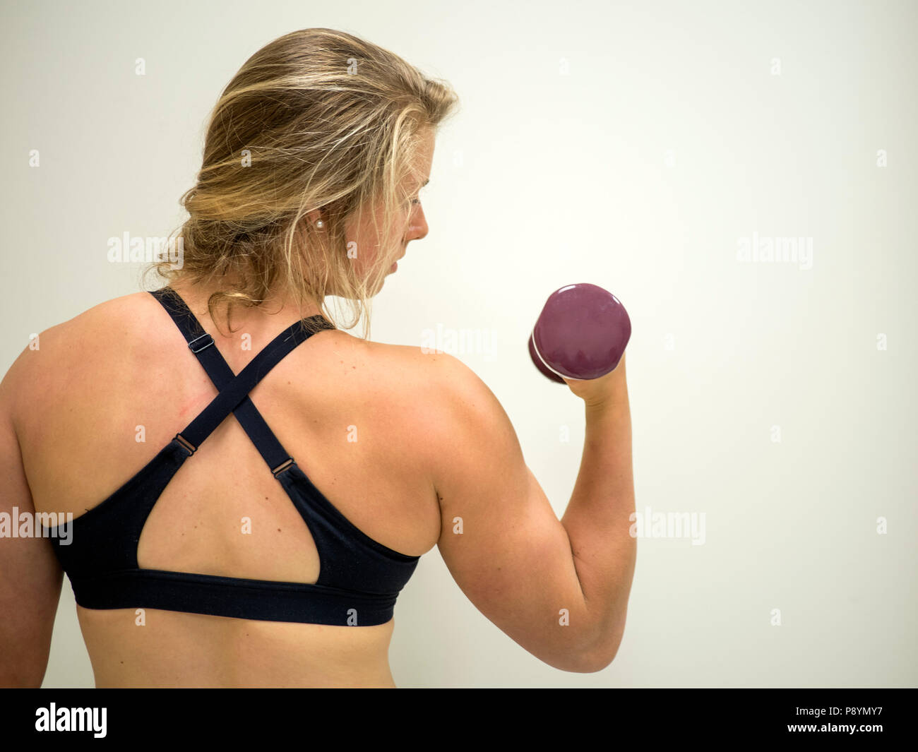 Strong female woman doing biceps pour l'exercice dans la salle de sport Banque D'Images