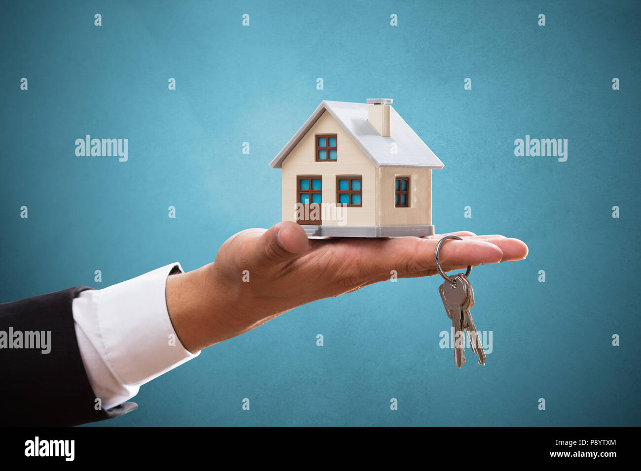 La main d'affaires avec la chambre et la clé sur fond bleu Banque D'Images