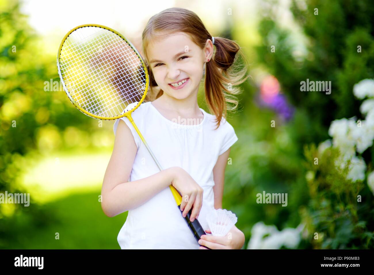 Cute little girl playing badminton à l'extérieur par beau jour d'été Banque D'Images