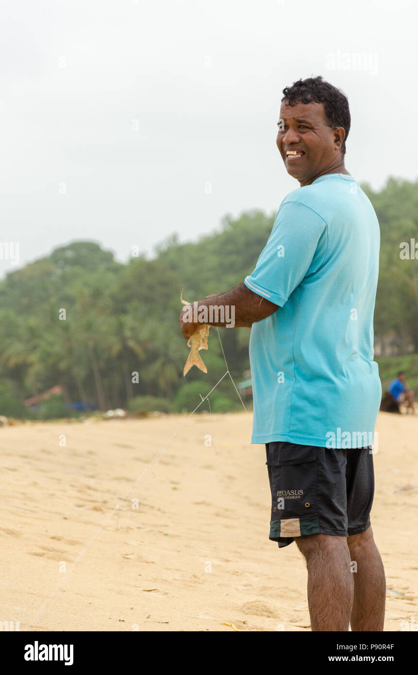Smiling portrait d'un pêcheur local Goan tenant un poisson à Betul Beach, Cavelossim, Goa, Inde Banque D'Images
