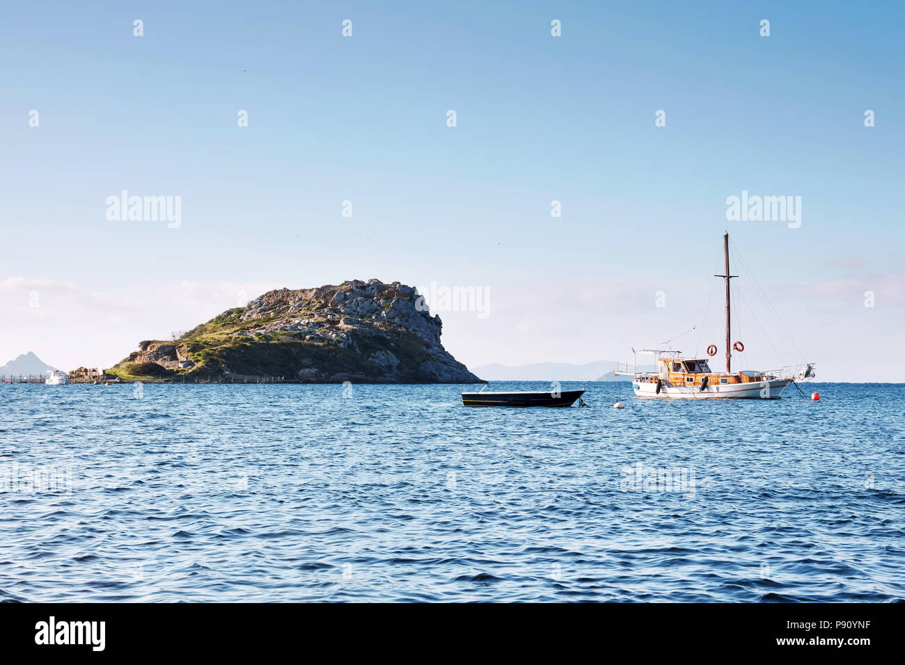 Un bateau et un yacht ancré près de l'île de lapin de l'antique civilisation de Myndos à Gumusluk Bodrum Mugla Turquie Banque D'Images