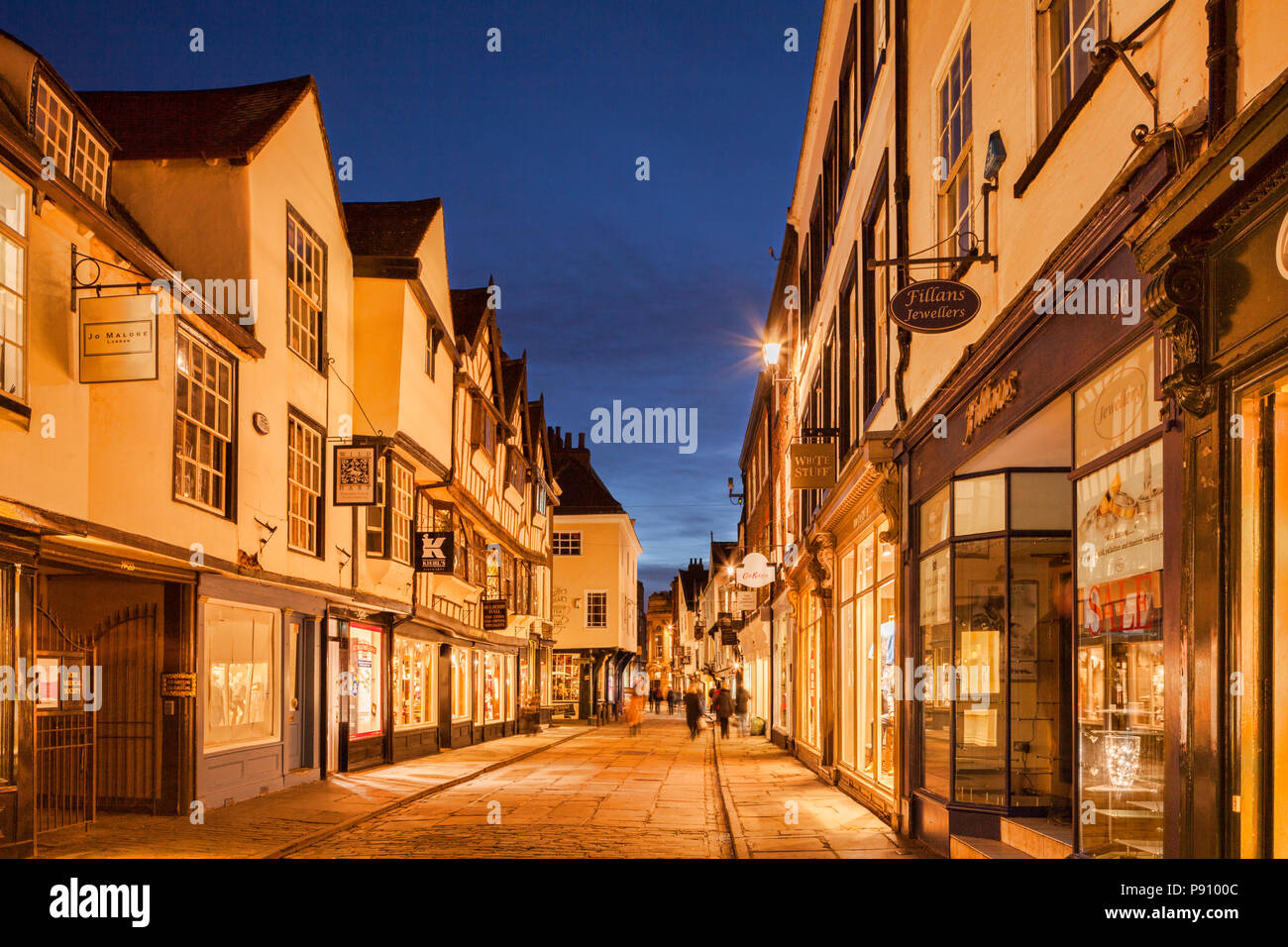 Twilight in Stonegate, York, North Yorkshire, Angleterre, Royaume-Uni. Légèrement floue Shoppers motion en raison d'une longue exposition. Banque D'Images