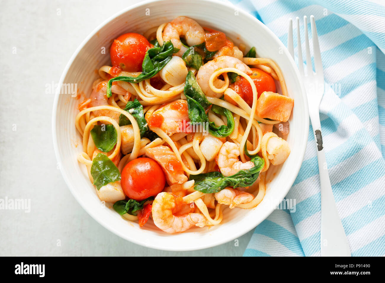 Linguine aux fruits de mer crevettes, pétoncles et saumon, Épinards et tomates Banque D'Images