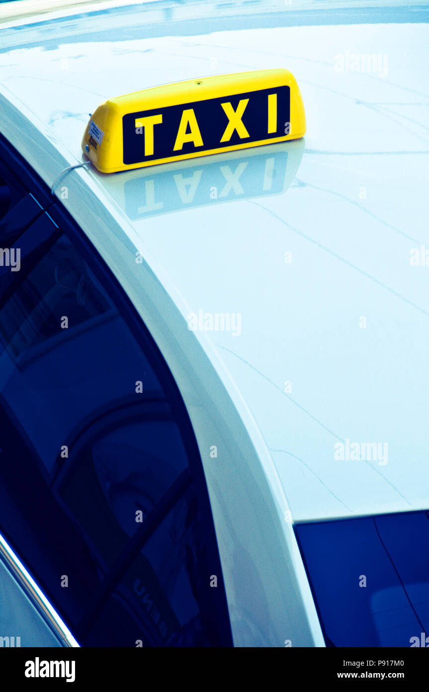 Yellow taxi cab signe sur le toit d'une voiture bleue Banque D'Images