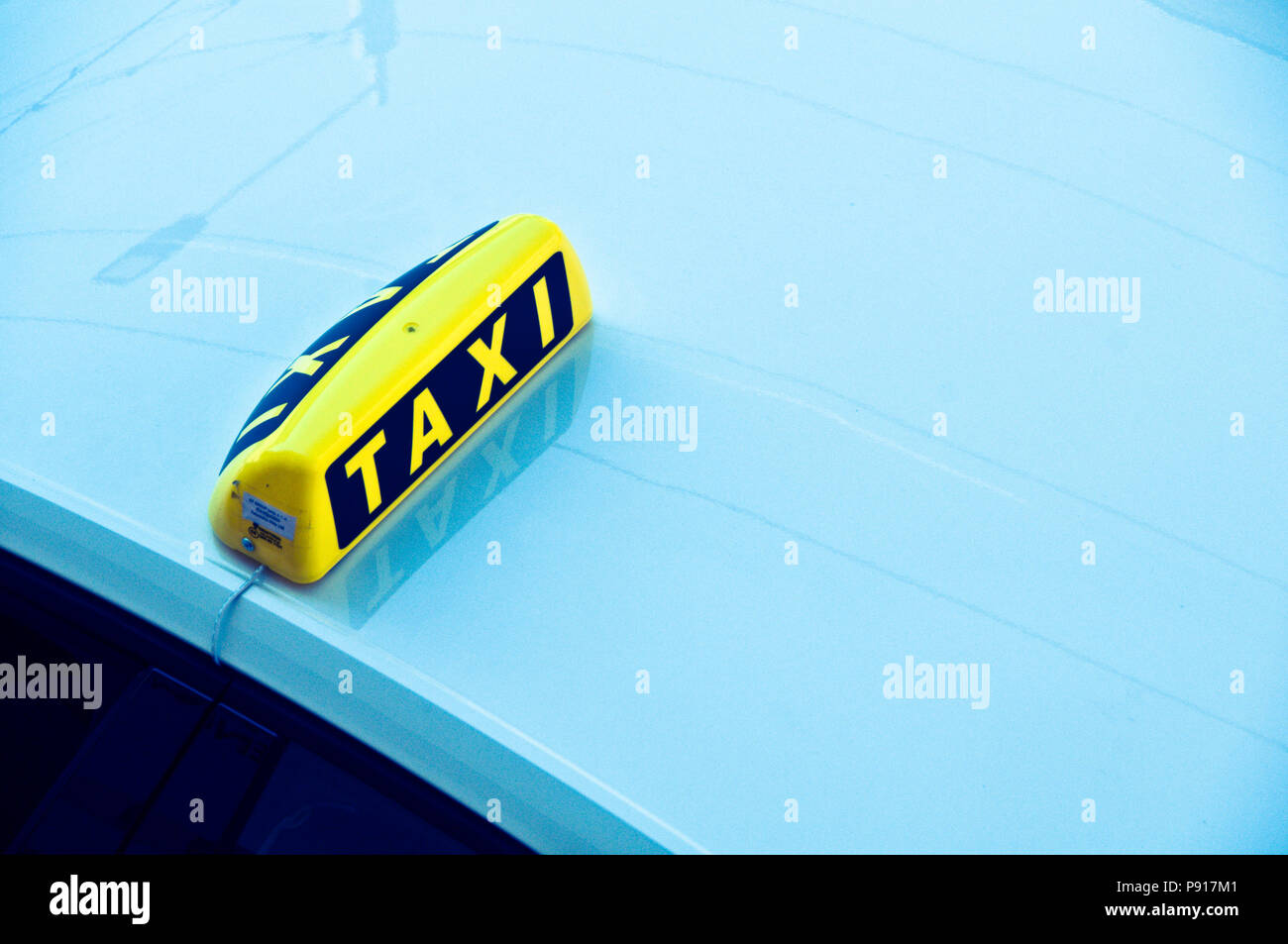 Yellow taxi cab signe sur le toit d'une voiture bleue Banque D'Images