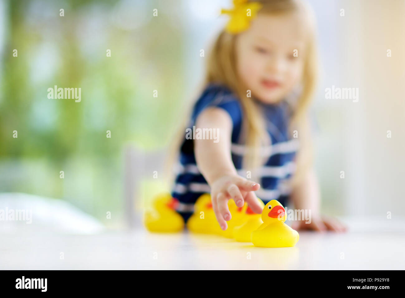 Jolie petite fille jouant avec les canetons en caoutchouc à la maison. Joli jouet enfant s'amusant avec les canards. Banque D'Images