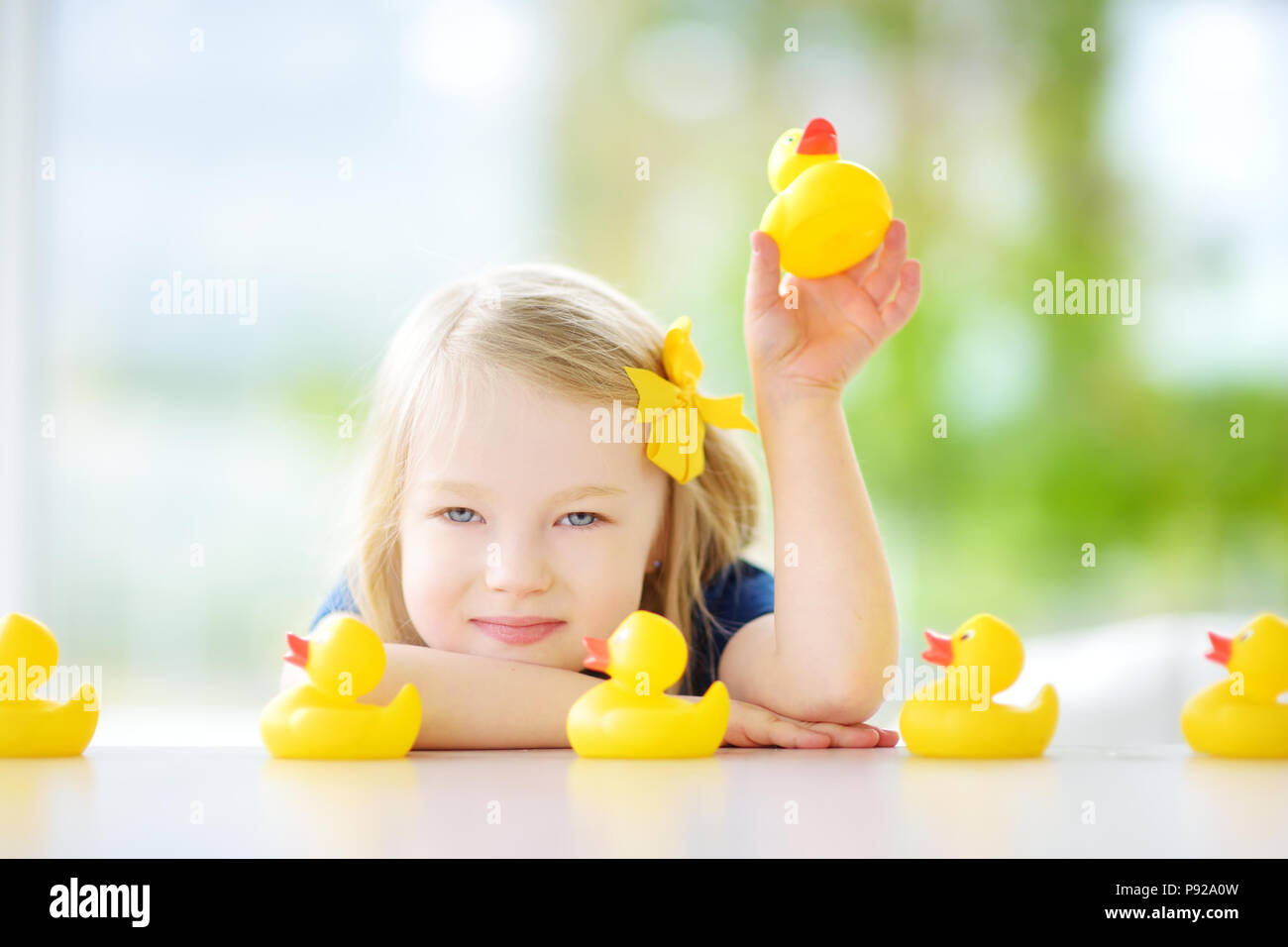 Jolie petite fille jouant avec les canetons en caoutchouc à la maison. Joli jouet enfant s'amusant avec les canards. Banque D'Images