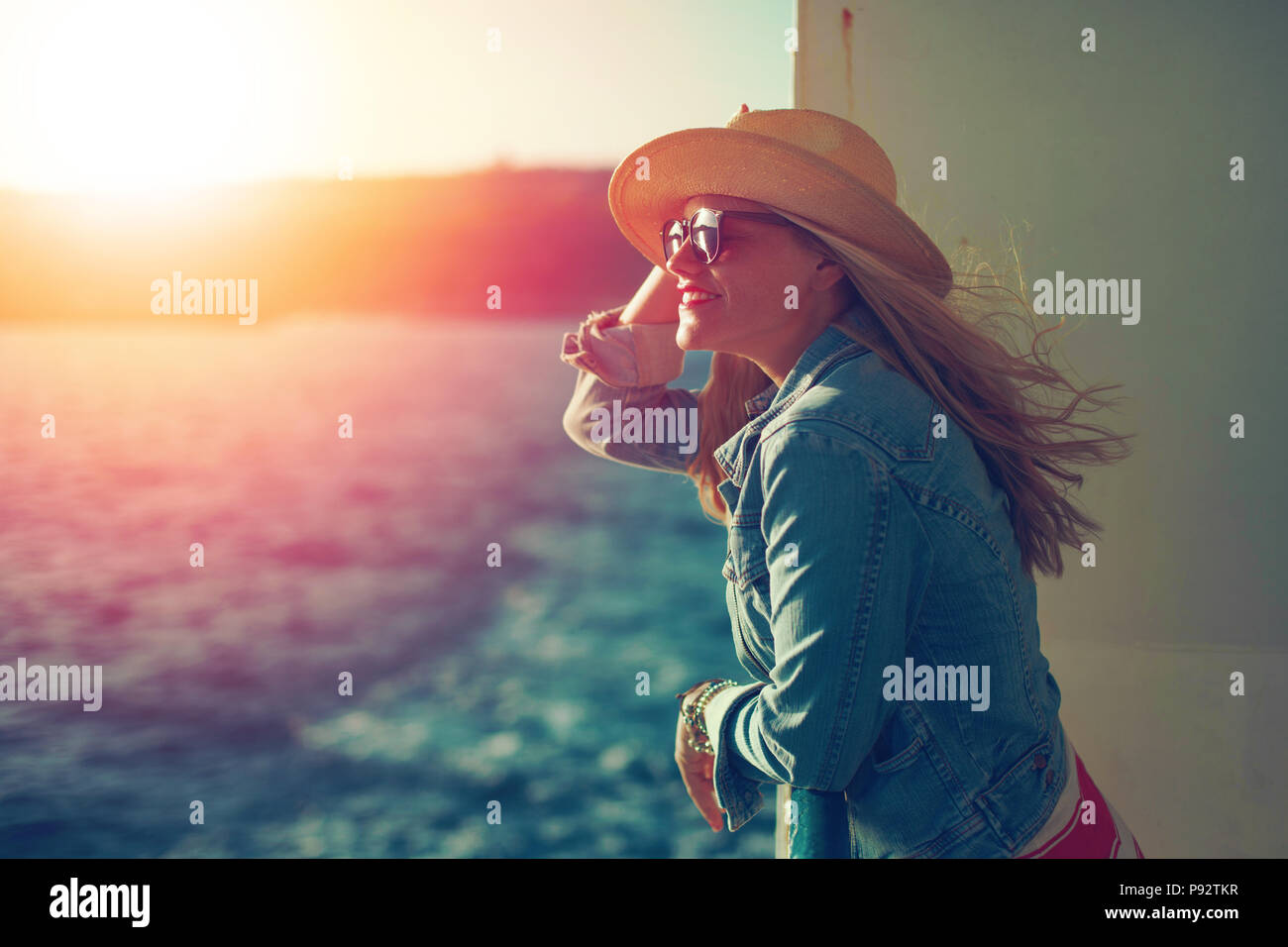 Jeune femme blonde traveler sur mer en hat à l'écart dans le coucher du soleil Banque D'Images