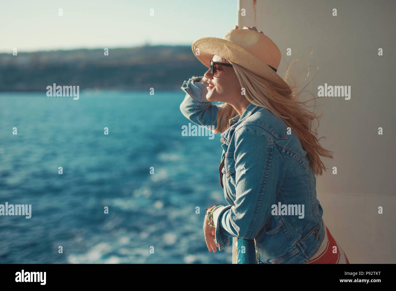 Young blonde woman in hat on cruise ship looking away Banque D'Images