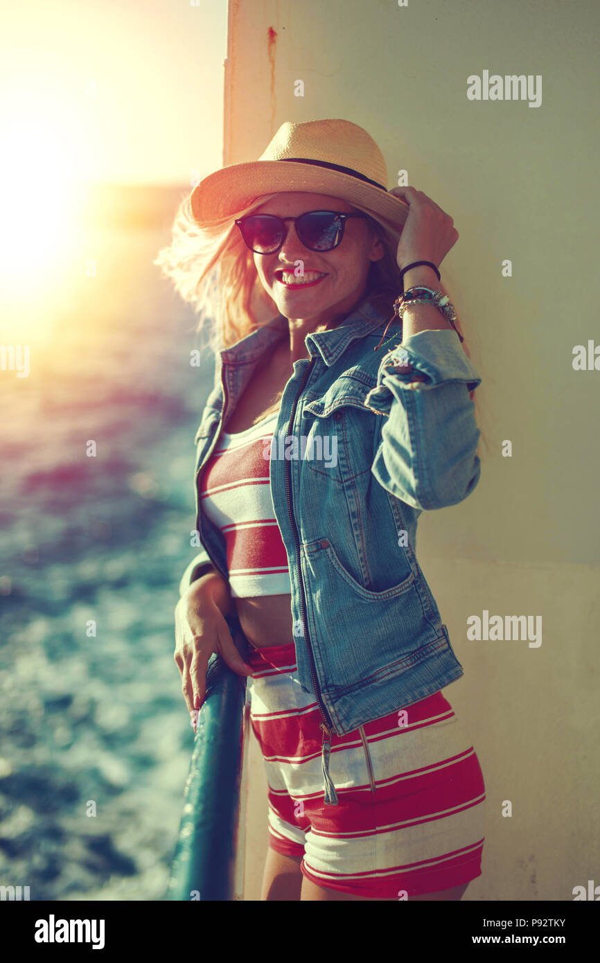 Heureux jeune voyageur woman holding hat sur bateau de croisière dans le coucher du soleil Banque D'Images