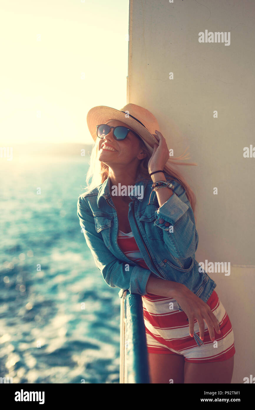 Happy young blonde woman holding hat on cruise ship Banque D'Images