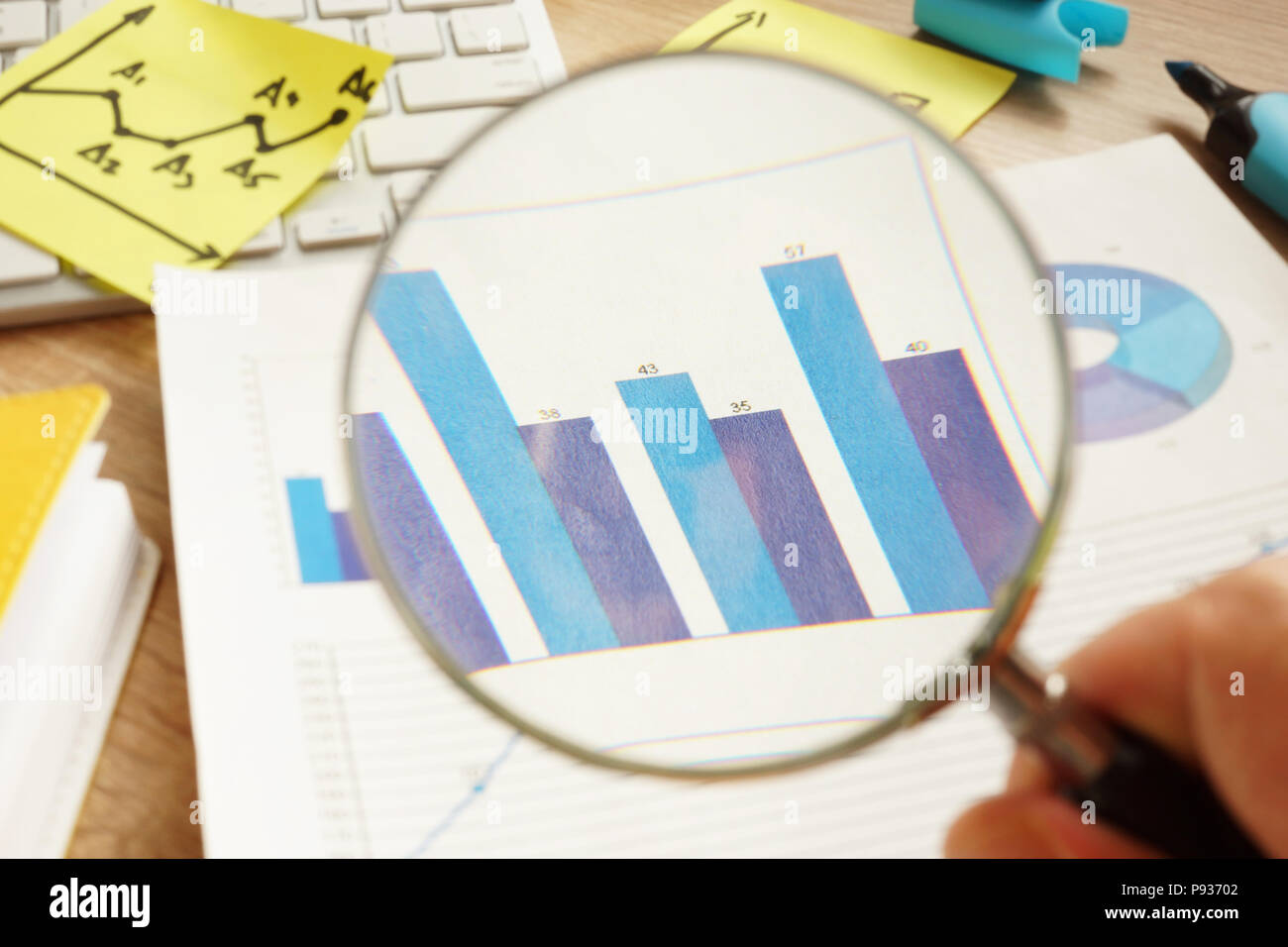 Vérification d'affaires. L'homme est à la recherche à travers une loupe sur les tableaux financiers. Banque D'Images