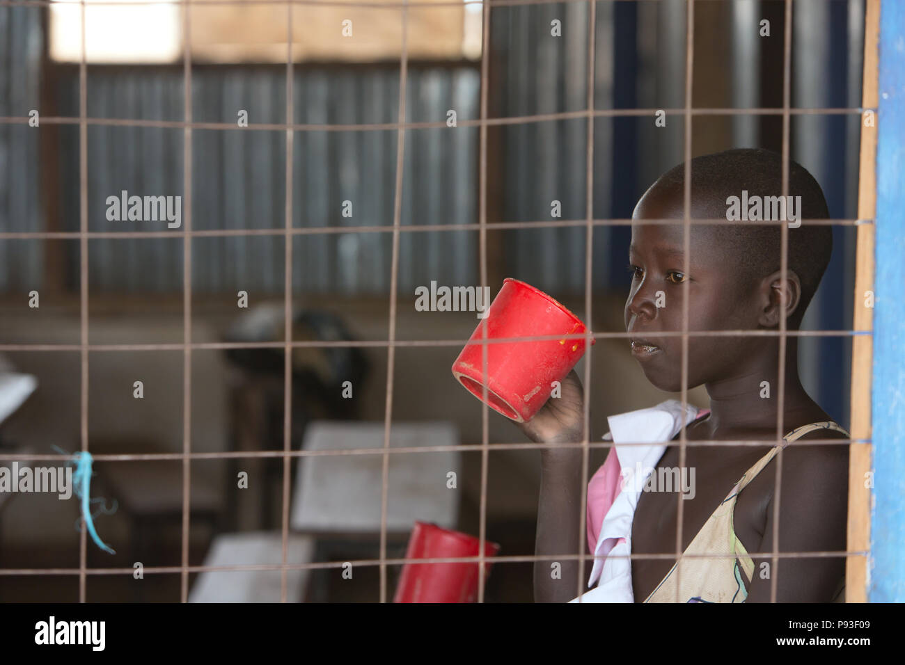 Kakuma, Kenya - jeune étudiant de boire une tasse dans une salle de classe. L'école dans le camp de réfugiés Kakuma. Banque D'Images