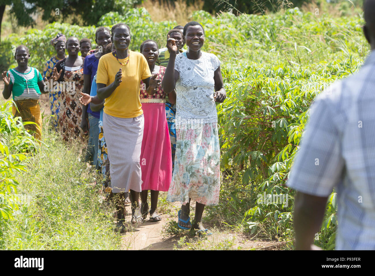 D'Adjumani, Ouganda - des femmes d'une communauté villageoise rencontrez un chantant et dansant sur un chemin. Banque D'Images