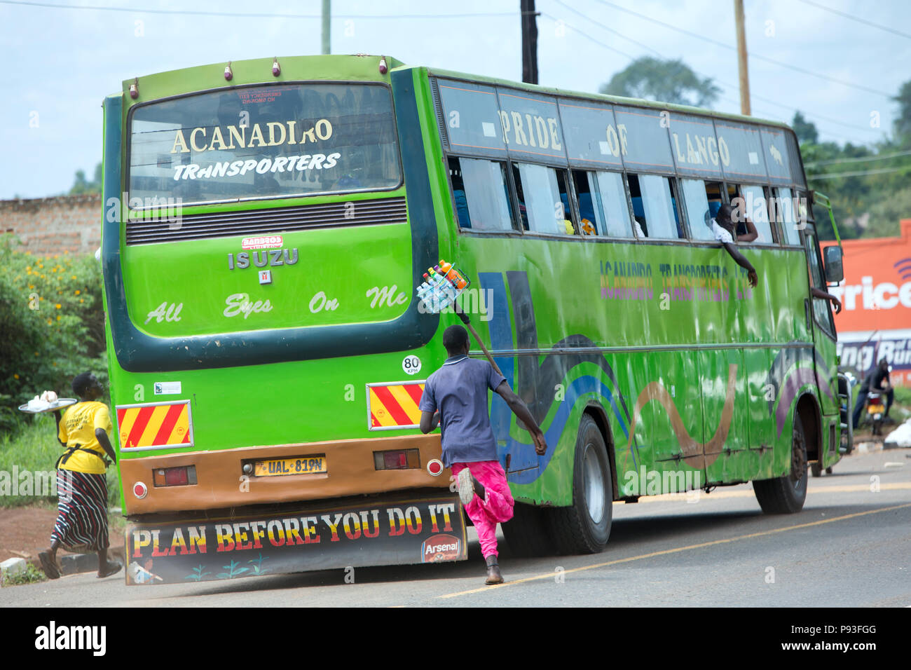 Kamdini, Ouganda - Flying courtiers à un arrêt de bus. Les habitants suivent un bus de banlieue avec des marchandises. Banque D'Images