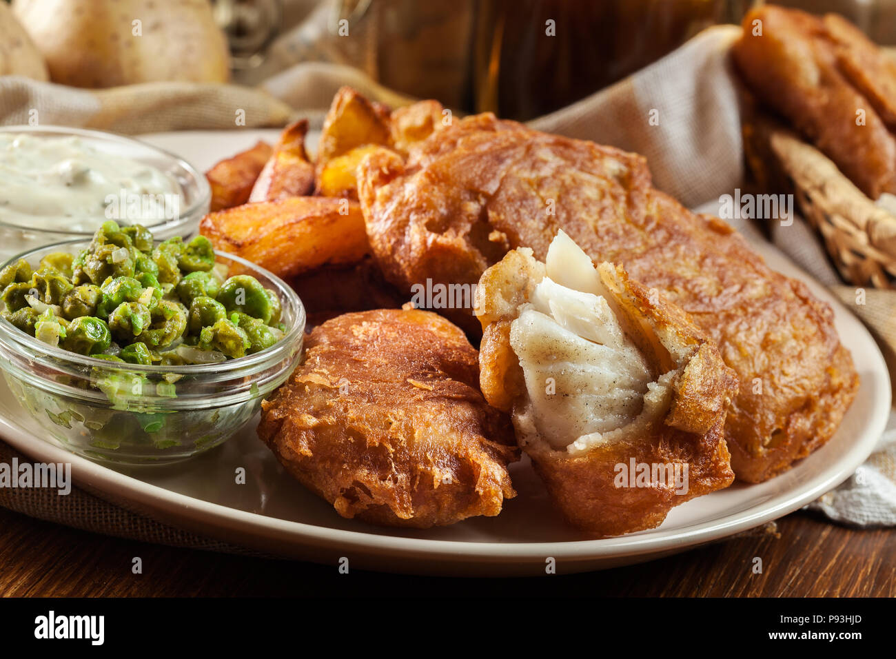 Le poisson dans la pâte traditionnelle de la bière et des frites avec de petits pois et sauce tartare Banque D'Images
