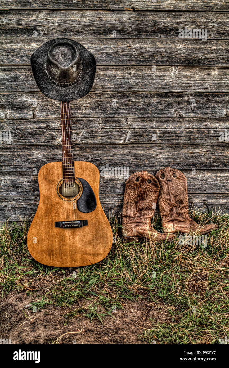 Acoutic guitare, chapeau de cowboy, bottes de cowboy et ancienne ferme de paroi de l'habitacle. Les régions rurales de l'Alberta, Canada. Banque D'Images