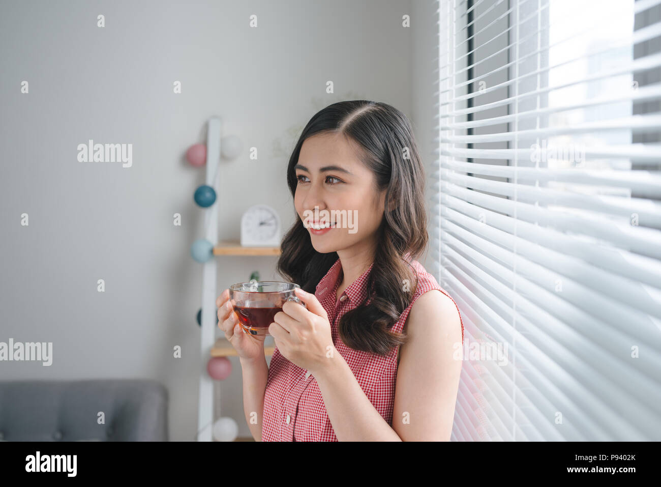 Jeune femme de boire du café ou du thé pendant que travailler ou étudier à la maison Banque D'Images