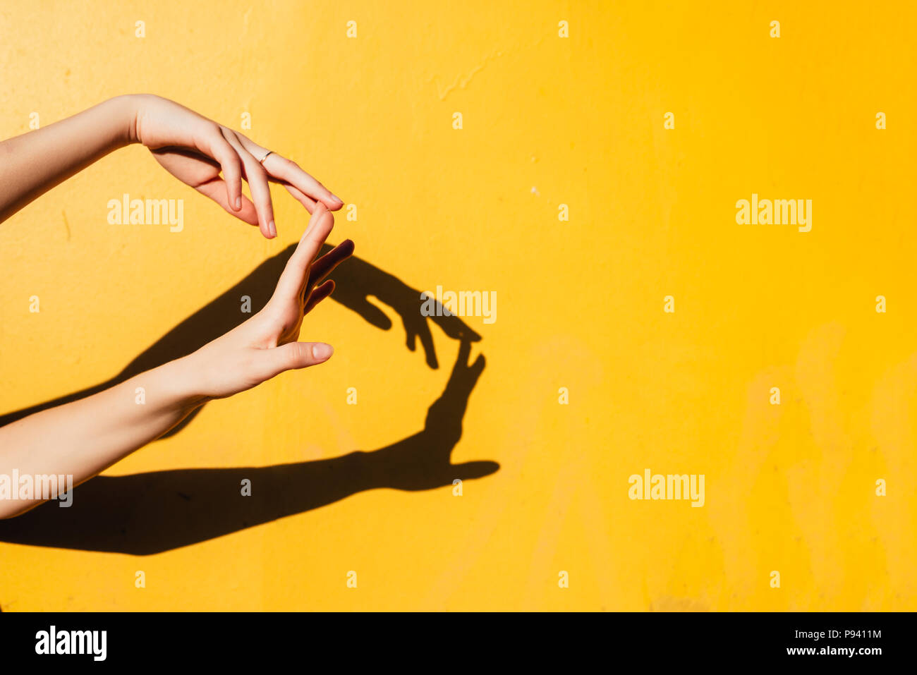 La main féminine. Summer girl teen danser sous la lumière directe du soleil. Bonheur Minimal Art Concept, fermer des mains avec shandows silhoutte of mountain range at sunset sur jaune backgroun Banque D'Images