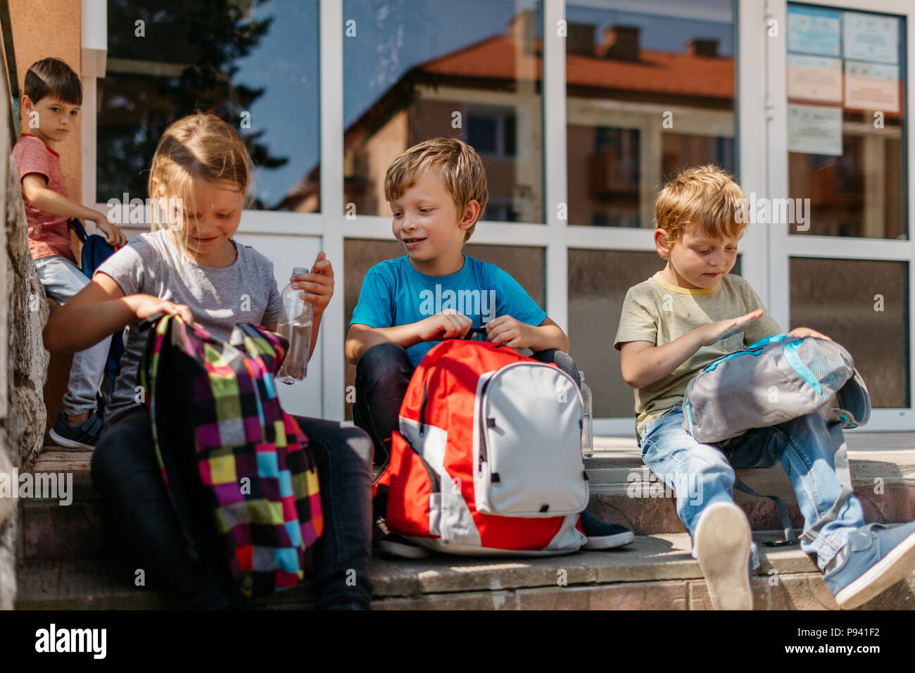Les jeunes élèves à la pause. Des enfants assis sur des escaliers à l'extérieur de l'école. Banque D'Images