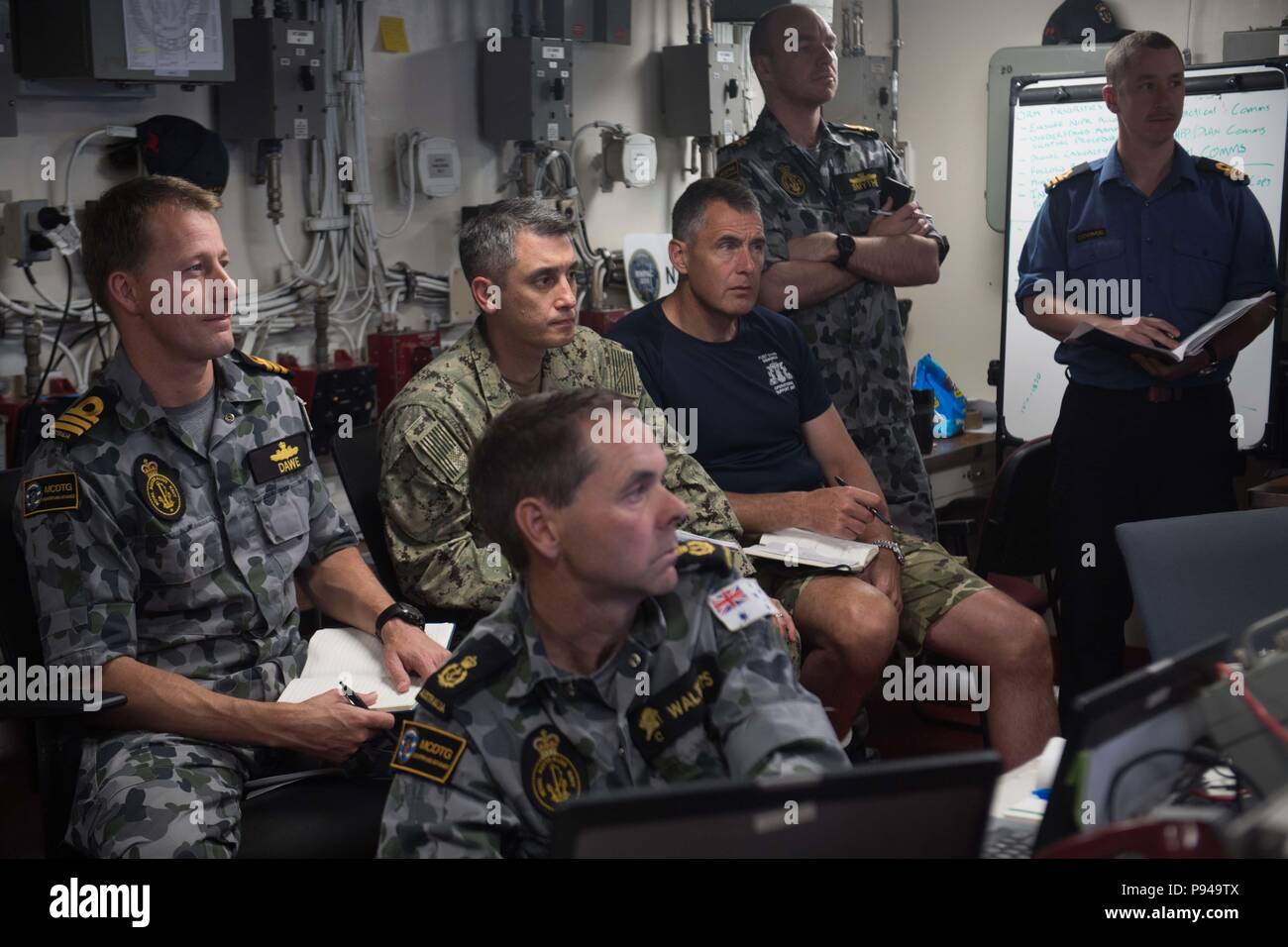 180711-N-OW019-1167 de l'OCÉAN PACIFIQUE (Juillet 11, 2018) Les marins de la Royal Navy, l'US Navy, de la Royal Australian Navy et de la Marine royale du Canada, de se rassembler dans le bureau logistique tactique à bord du navire de débarquement quai amphibie USS Harpers Ferry (LSD 49), au cours d'une brève mise à jour de commande, à l'appui de Rim of the Pacific (RIMPAC), le 11 juillet. Vingt-cinq nations, 46 navires, 5 sous-marins, environ 200 avions et 25 000 personnes participent à l'EXERCICE RIMPAC du 27 juin au 2 août dans et autour des îles Hawaï et la Californie du Sud. Le plus grand exercice maritime international, de l'EXERCICE RIMPAC, prov Banque D'Images