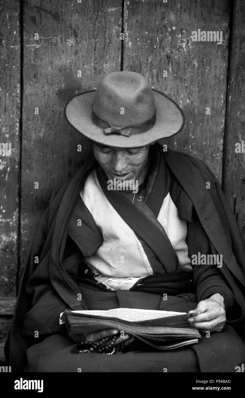 Un moine bouddhiste tibétain lit les écritures sur le BARKHOR () - Bazar tibétain de Lhassa, Tibet Banque D'Images