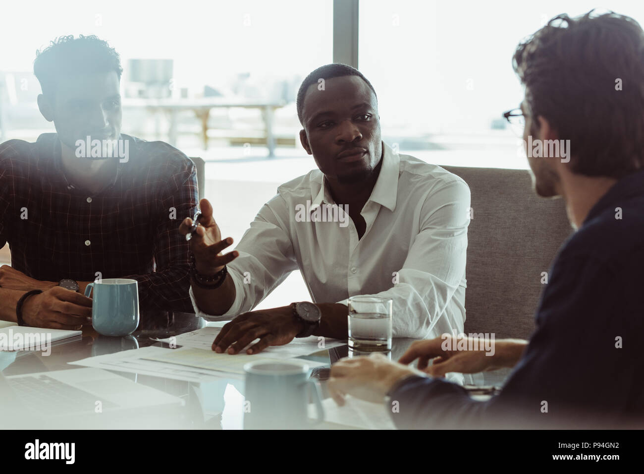 Businesspeople travailler assis à une table de conférence en fonction. Trois hommes dans une réunion à discuter d'affaires officielles de travail. Banque D'Images