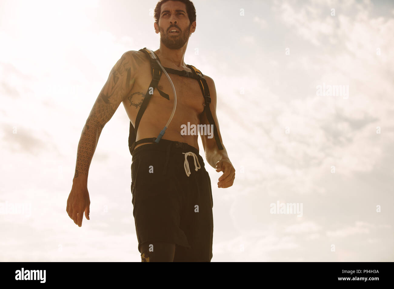 Jeune homme sain contre ciel. Low angle view of male athlete avec sac à l'extérieur. Banque D'Images