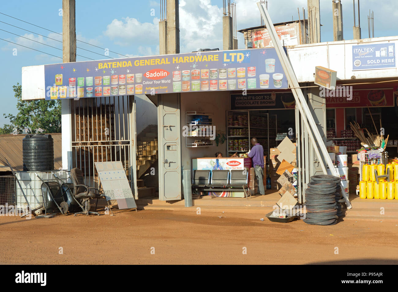Ville de Wakiso, Ouganda - Scène de rue. Un client achète la peinture dans un magasin de matériel. Banque D'Images