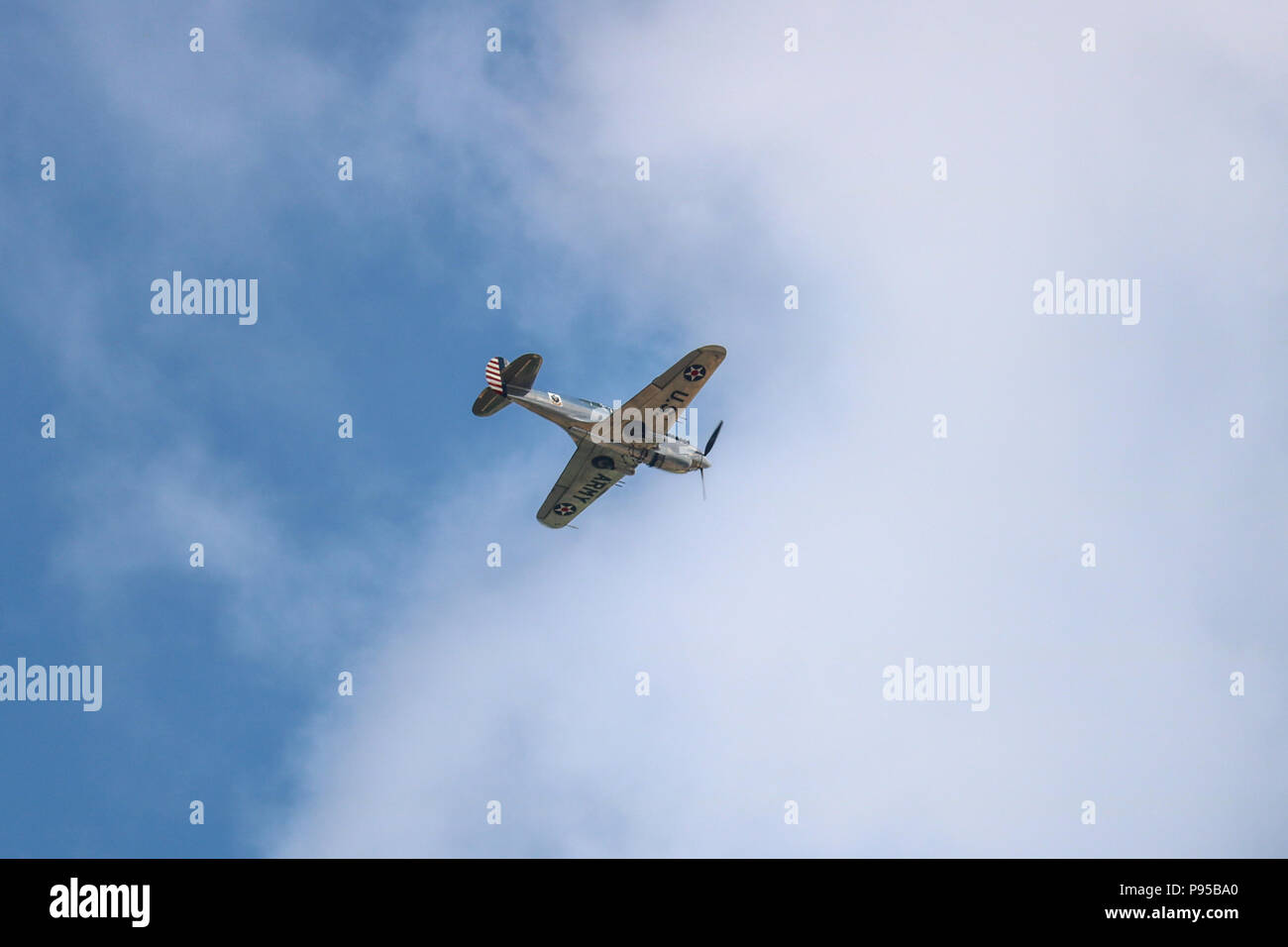 Un argent poli P40 Warhawk II vole au-dessous de nuage blanc cassé sur Cambridgeshire sur une journée ensoleillée. Banque D'Images