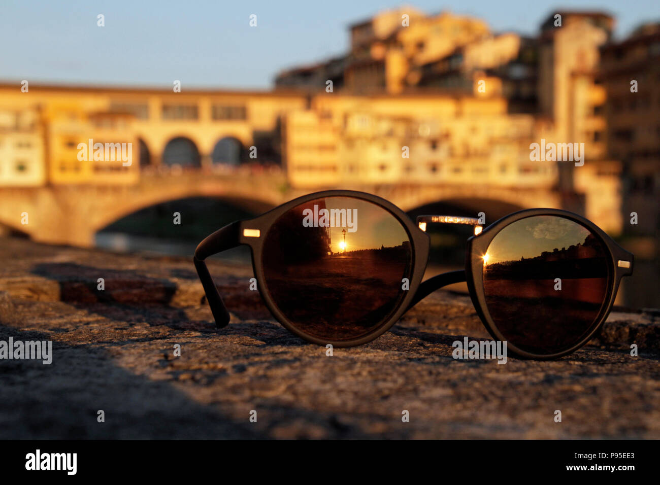 Le soleil couchant se reflétant dans une paire de lunettes de soleil avec le célèbre Ponte Vecchio de Florence, en Italie, dans l'arrière-plan Banque D'Images