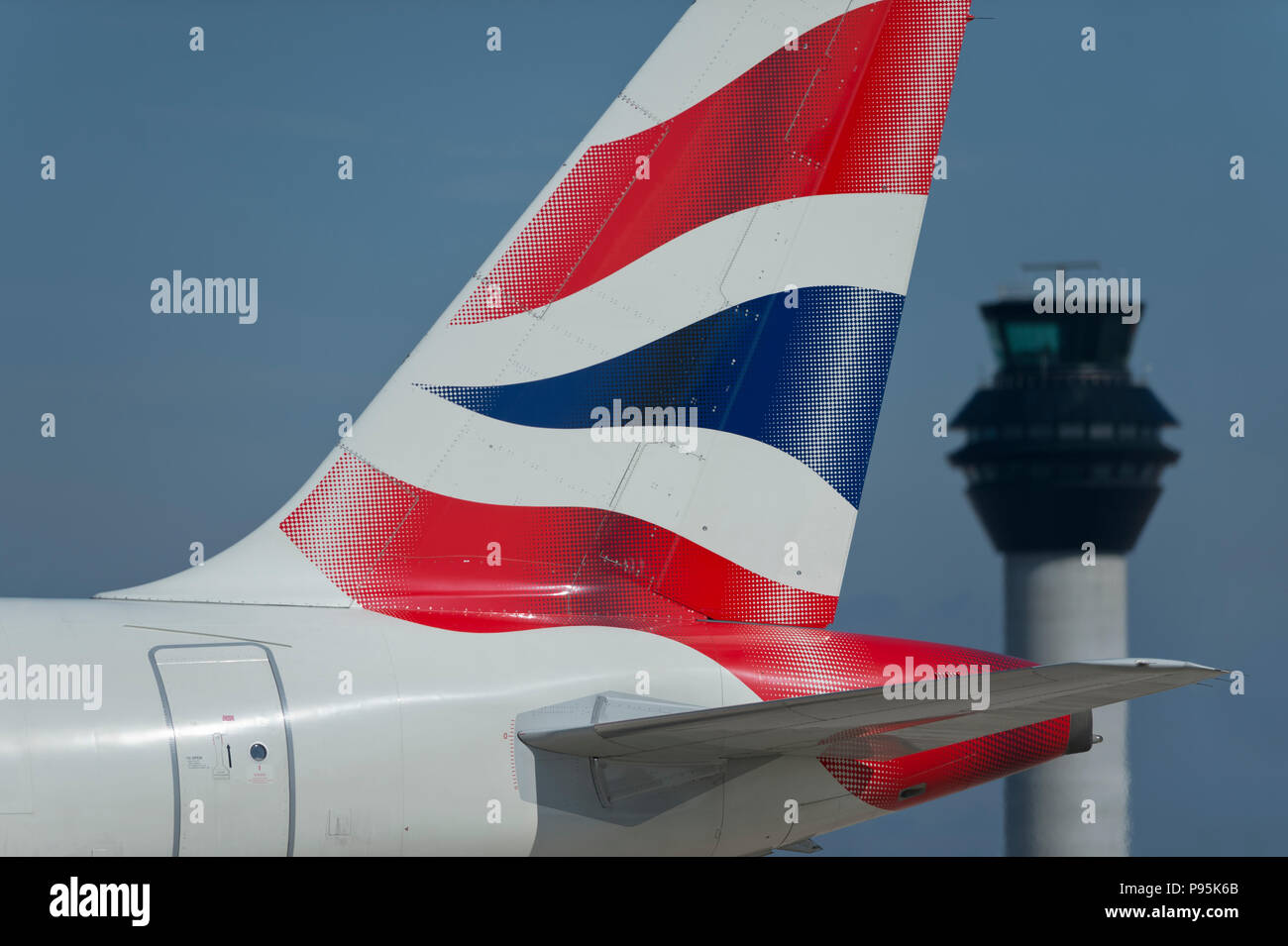 La tailfin d'un British Airways Airbus A319-131 circule le long de la piste en face de la tour de contrôle à l'aéroport de Manchester. Banque D'Images