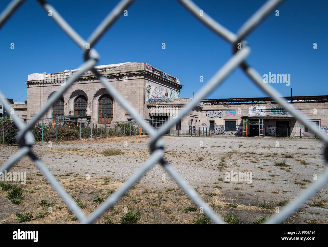 L'abandonné barricadèrent 16e Rue gare de West Oakland, Californie vue à travers une clôture à mailles de chaîne. Banque D'Images