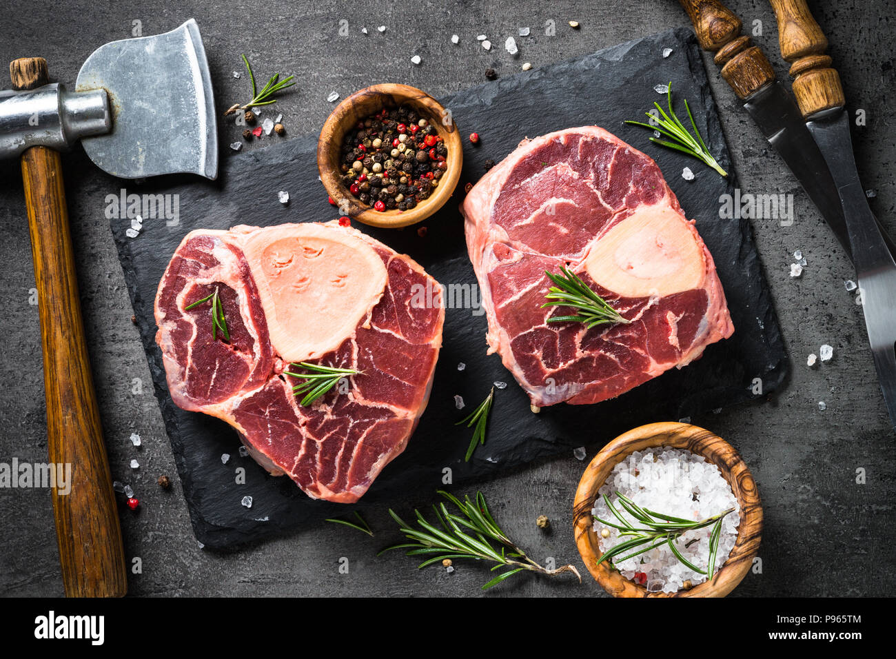 Steak de boeuf cru osso bucco sur fond ardoise noire. En viande. Vue d'en haut. Banque D'Images