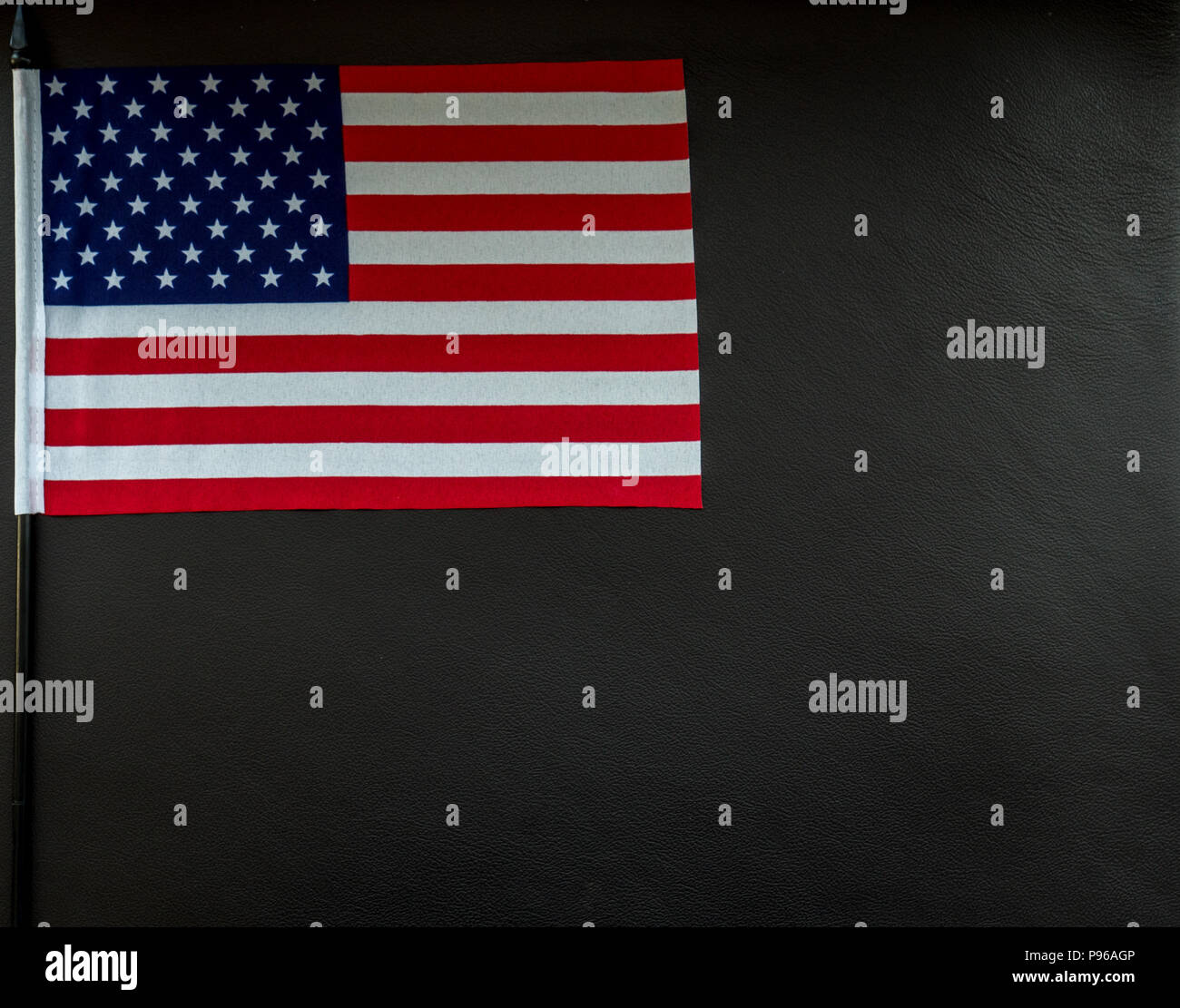 Petit drapeau américain sur la surface en cuir foncé avec un espace réservé au texte studio light Banque D'Images