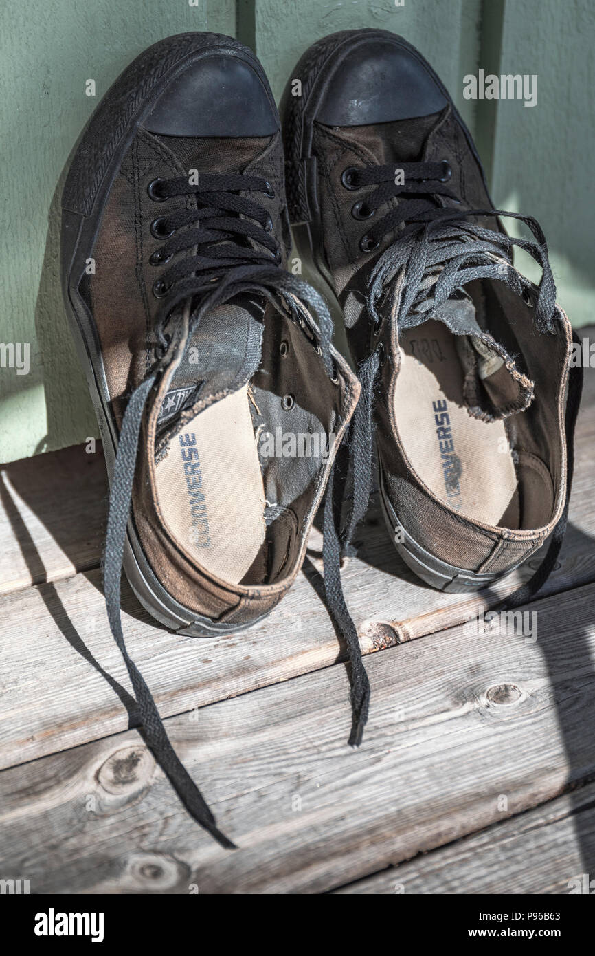 Vue rapprochée de classic noir usé chaussures Converse All Star appuyé contre mur Banque D'Images