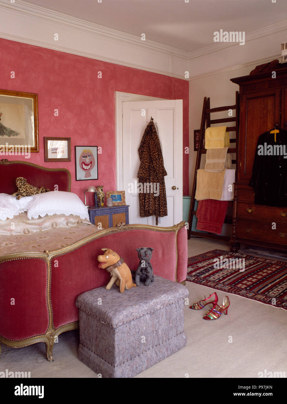 Les jouets mous sur pouf velours rose ci-dessous lit rembourré dans une chambre avec un papier peint rose années 90 Banque D'Images