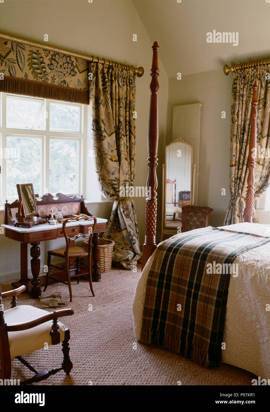 Plaid jeter sur le lit avec tourné posts en pays chambre avec des rideaux à  motifs et aveugle et tapis texturé Photo Stock - Alamy