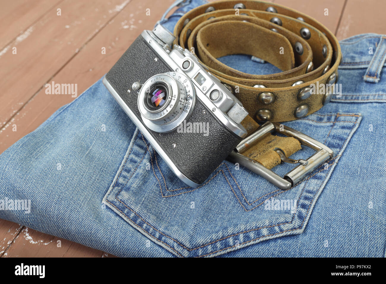 Vêtements, chaussures et accessoires - Vue de dessus Gros plan retro photo, caméra de ceinture de cuir et un jean bleu sur un fond de bois Banque D'Images
