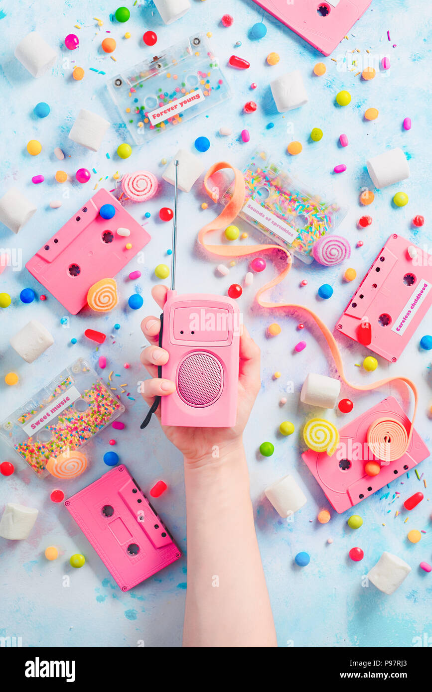 Candy cassettes et lecteur radio rétro rose dans une main. Les bonbons, les marmelades et sprinkles dans une musique agréable concept avec copie espace. Télévision couleur pastel avec des bonbons laïcs Banque D'Images