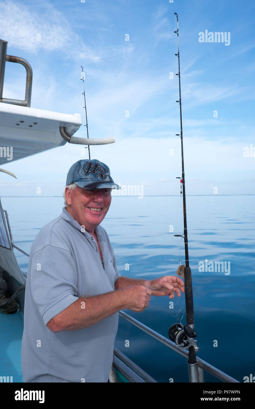 Senior smiling tourist sur bateau de pêche charte avec la tige dans la baie sans doute, loin du Nord District, Nouvelle-Zélande, NZ Banque D'Images