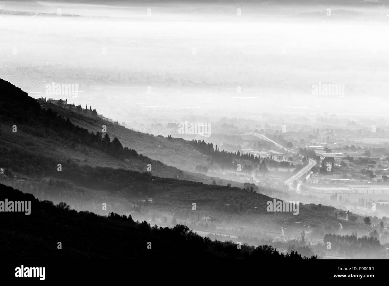 Belle vue aérienne de la vallée de l'Ombrie dans un matin d'hiver, avec du brouillard couvrant les arbres, maisons et rues Banque D'Images