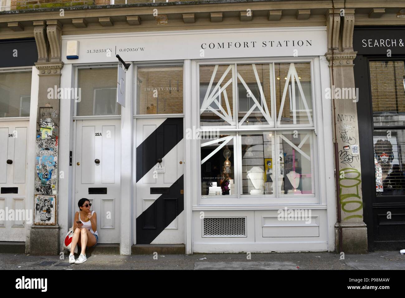 Jeune femme de manger une collation sur la porte à côté de la station de confort à Londres Banque D'Images