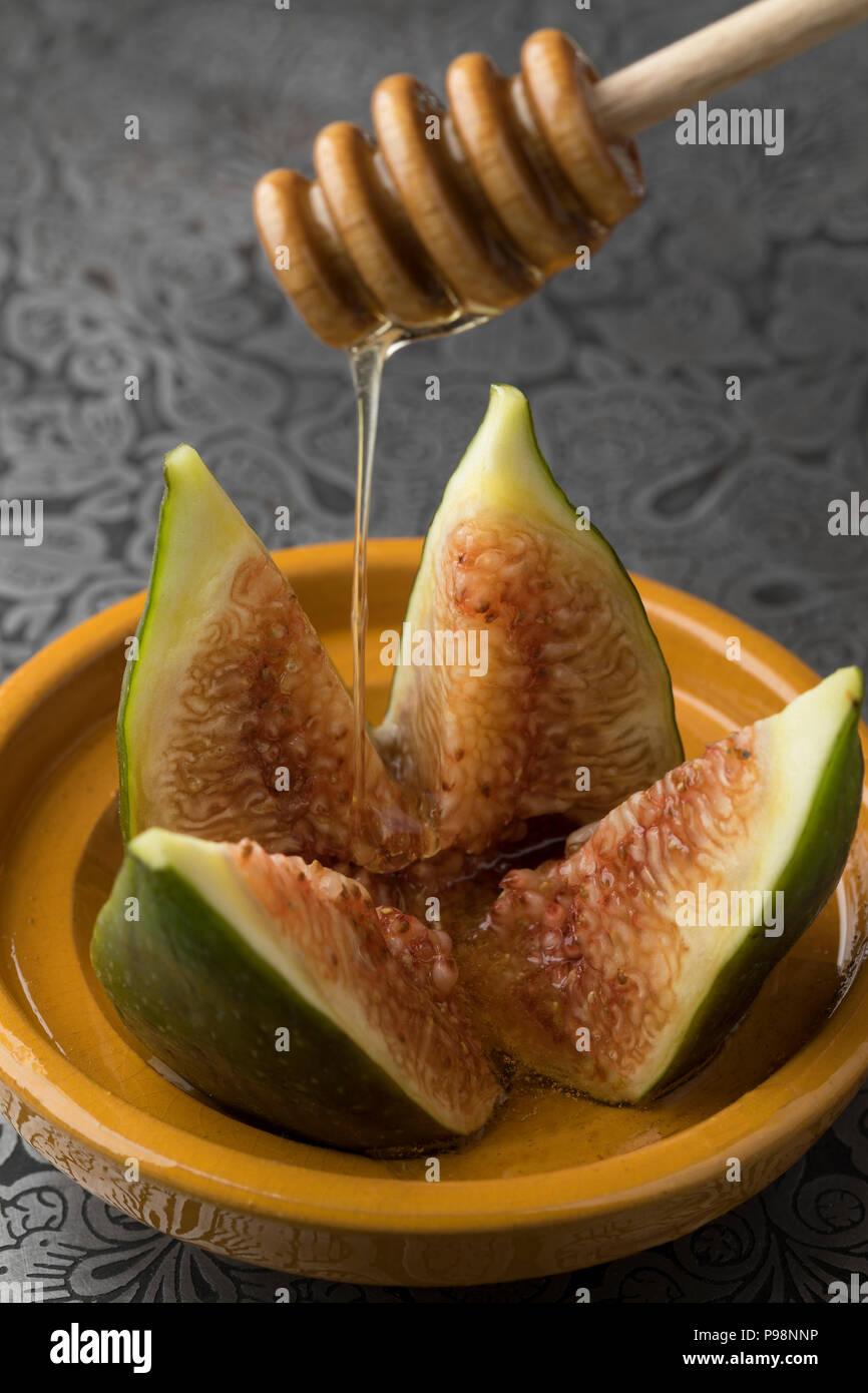 Fig frais mûrs sur un plat saupoudré avec du miel Banque D'Images