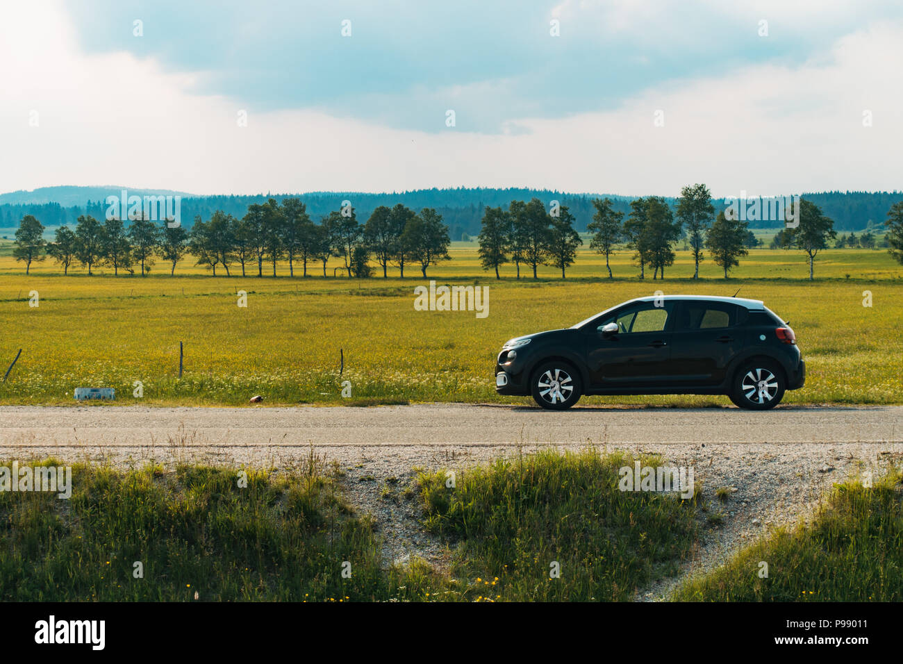 Une Citroën C3 à hayon en noir avec un toit blanc se trouve garé sur le côté de la route près de terres agricoles en Bosnie et Herzégovine Banque D'Images